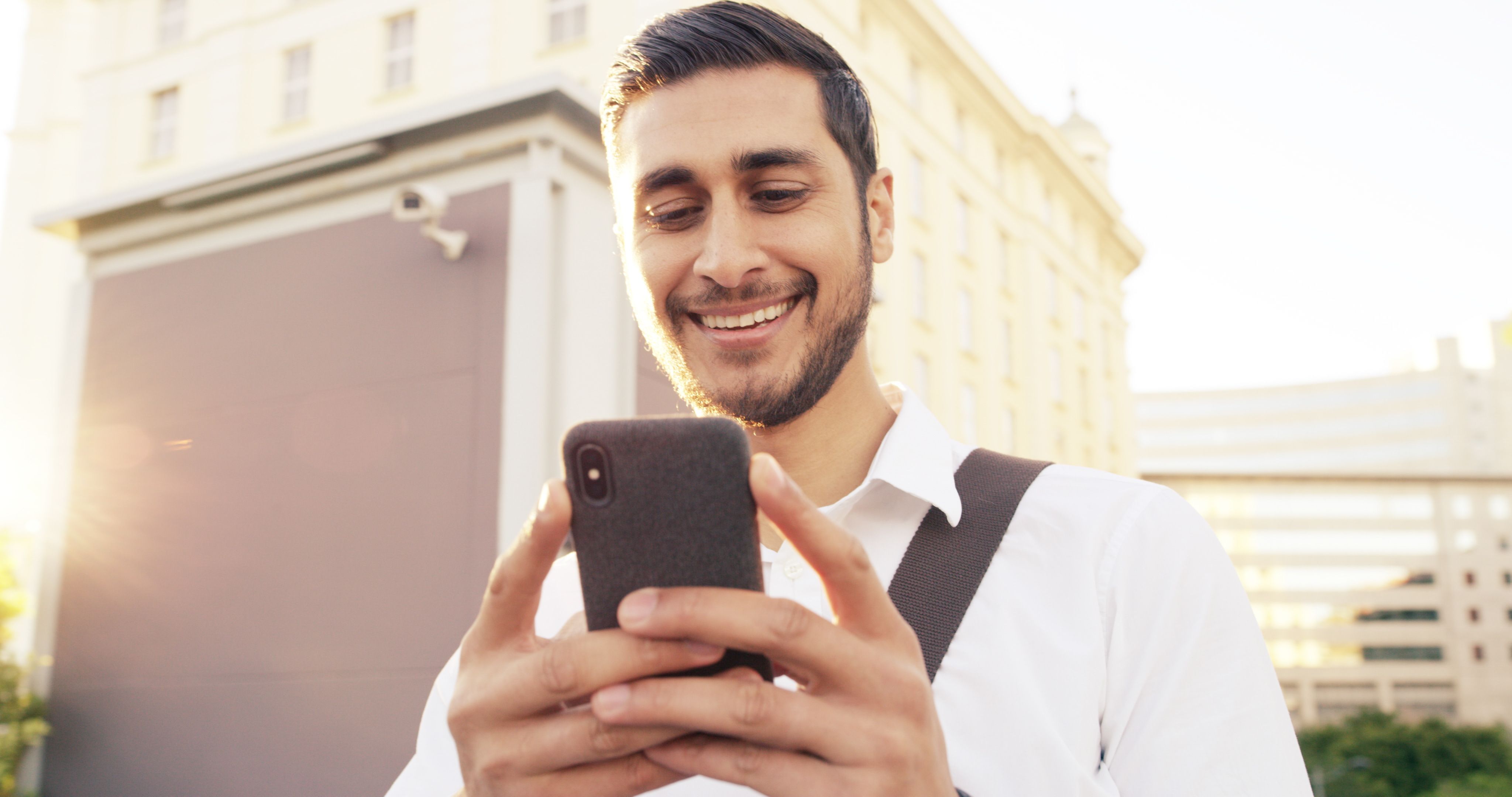 happy-businessman-typing-with-phone-city-communication-online-texting-chatting-man-tourist-traveler-with-smile-mobile-smartphone-network-connectivity-app-urban-town.jpg
