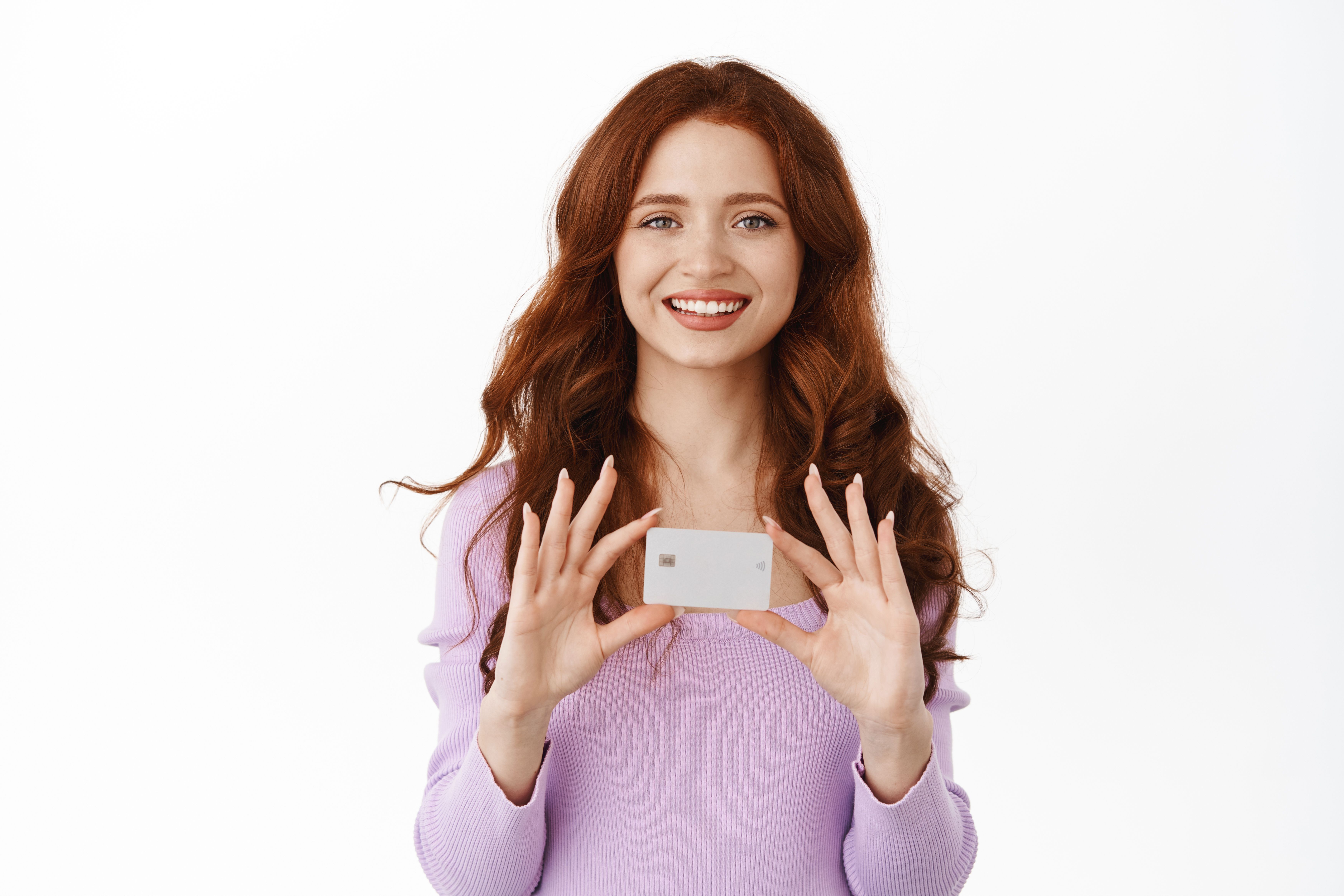 smiling-cute-girl-with-ginger-hair-shows-her-new-bank-credit-card-shopping-stores-contactless-buying-things-with-deposit-money-standing-white-background.jpg