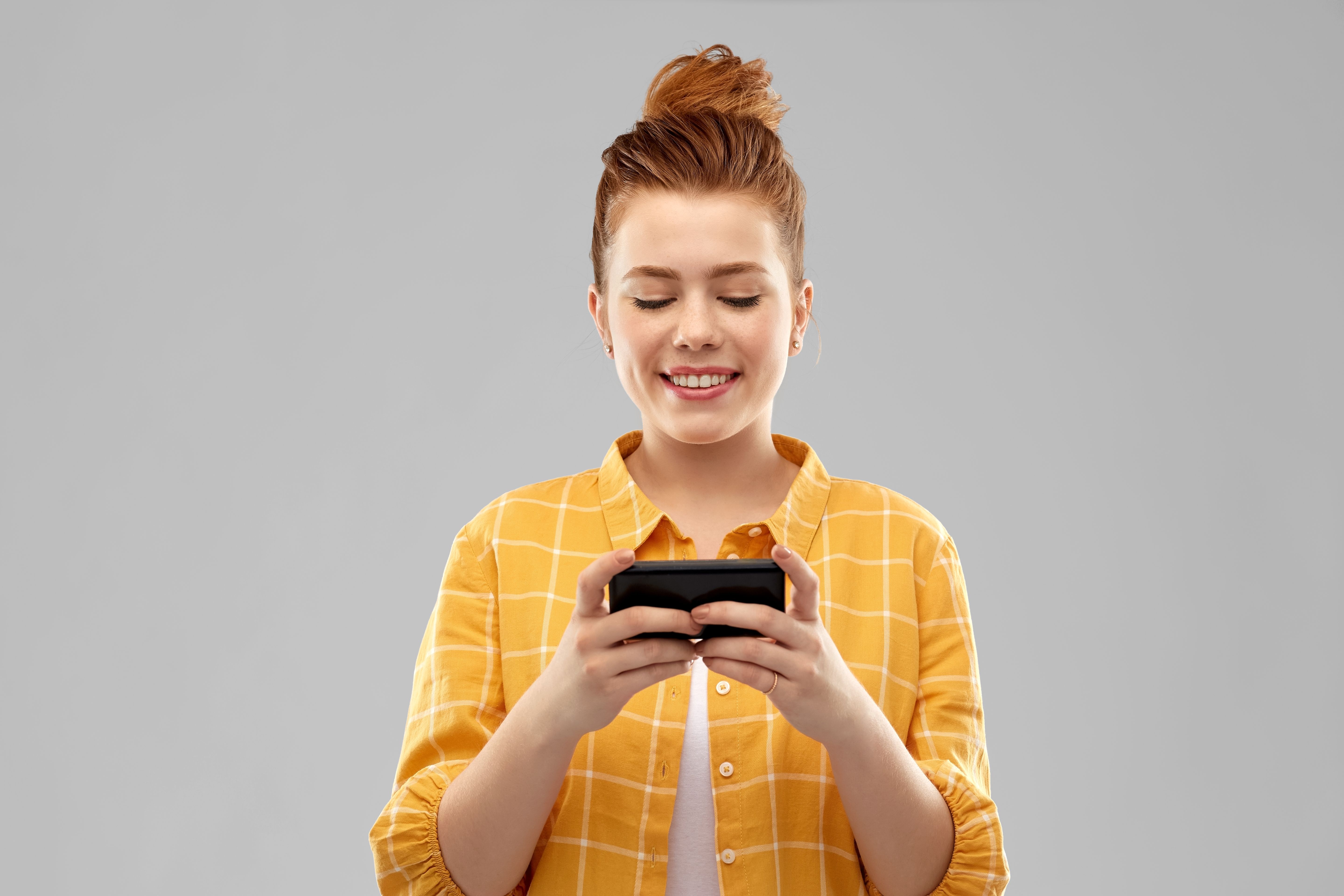 smiling-red-haired-teenage-girl-using-smartphone.jpg