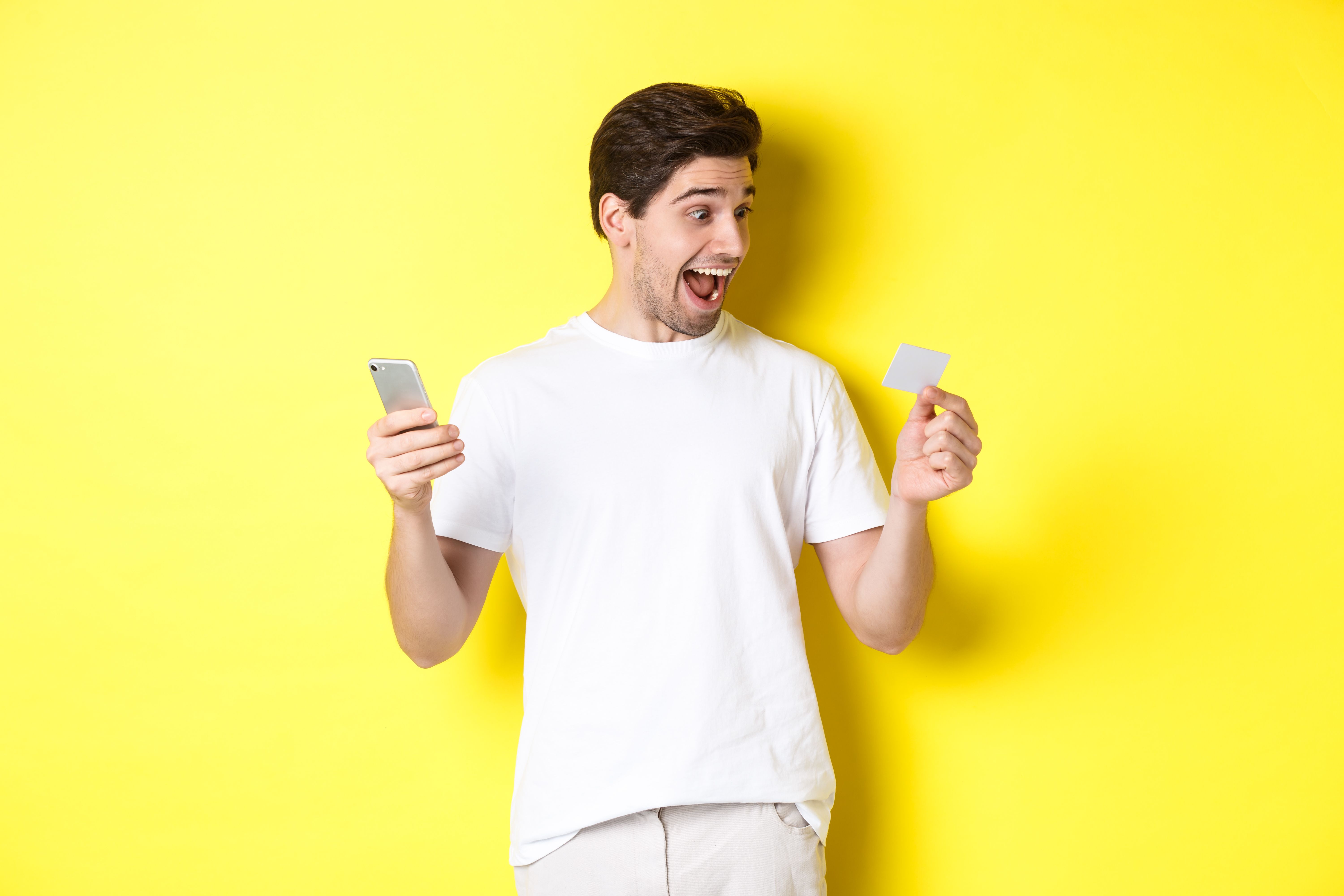 surprised-guy-holding-smartphone-credit-card-online-shopping-black-friday-standing-yellow-background.jpg