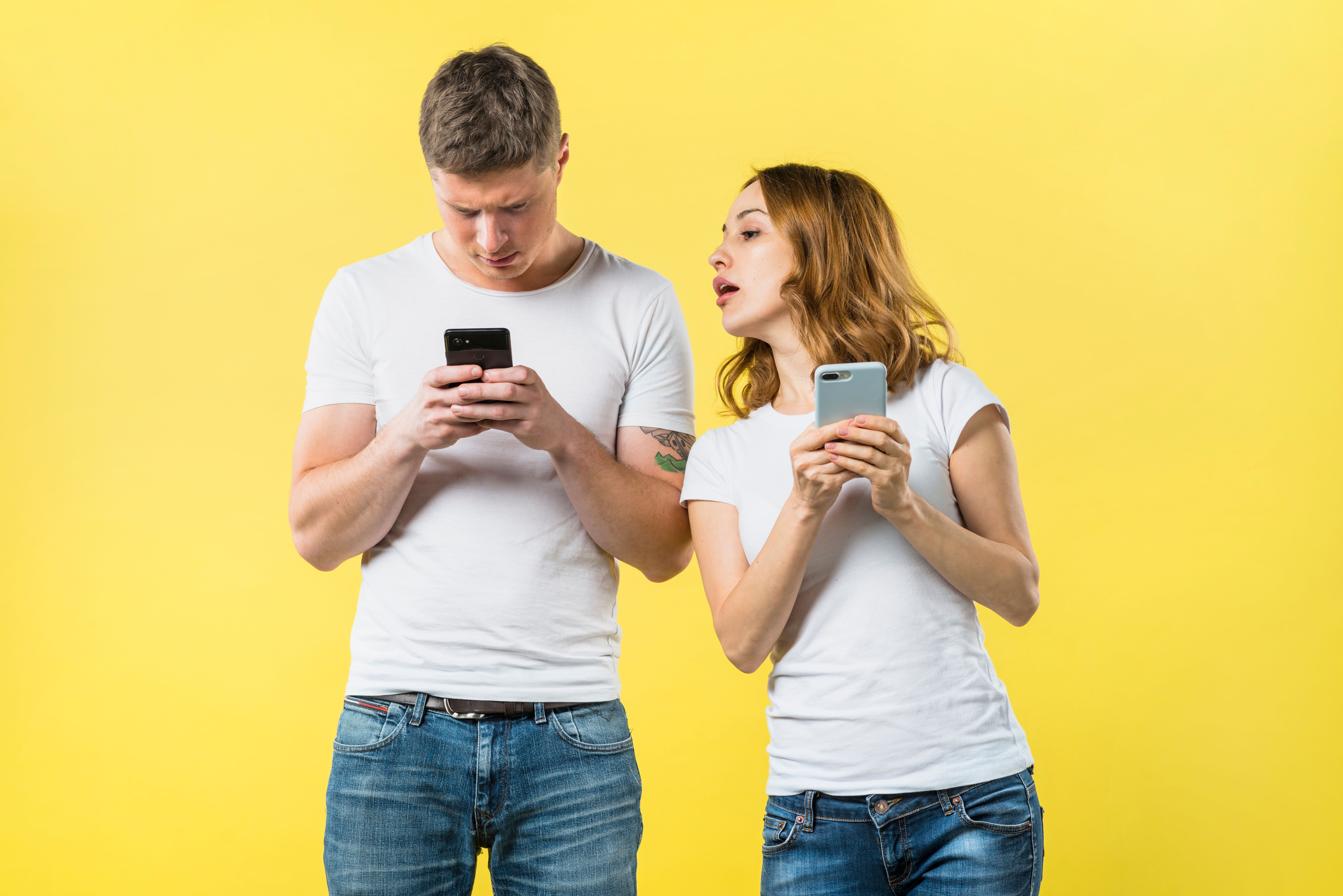 suspicious-girlfriend-spying-his-boyfriend-texting-mobile-phone-against-yellow-backdrop.jpg