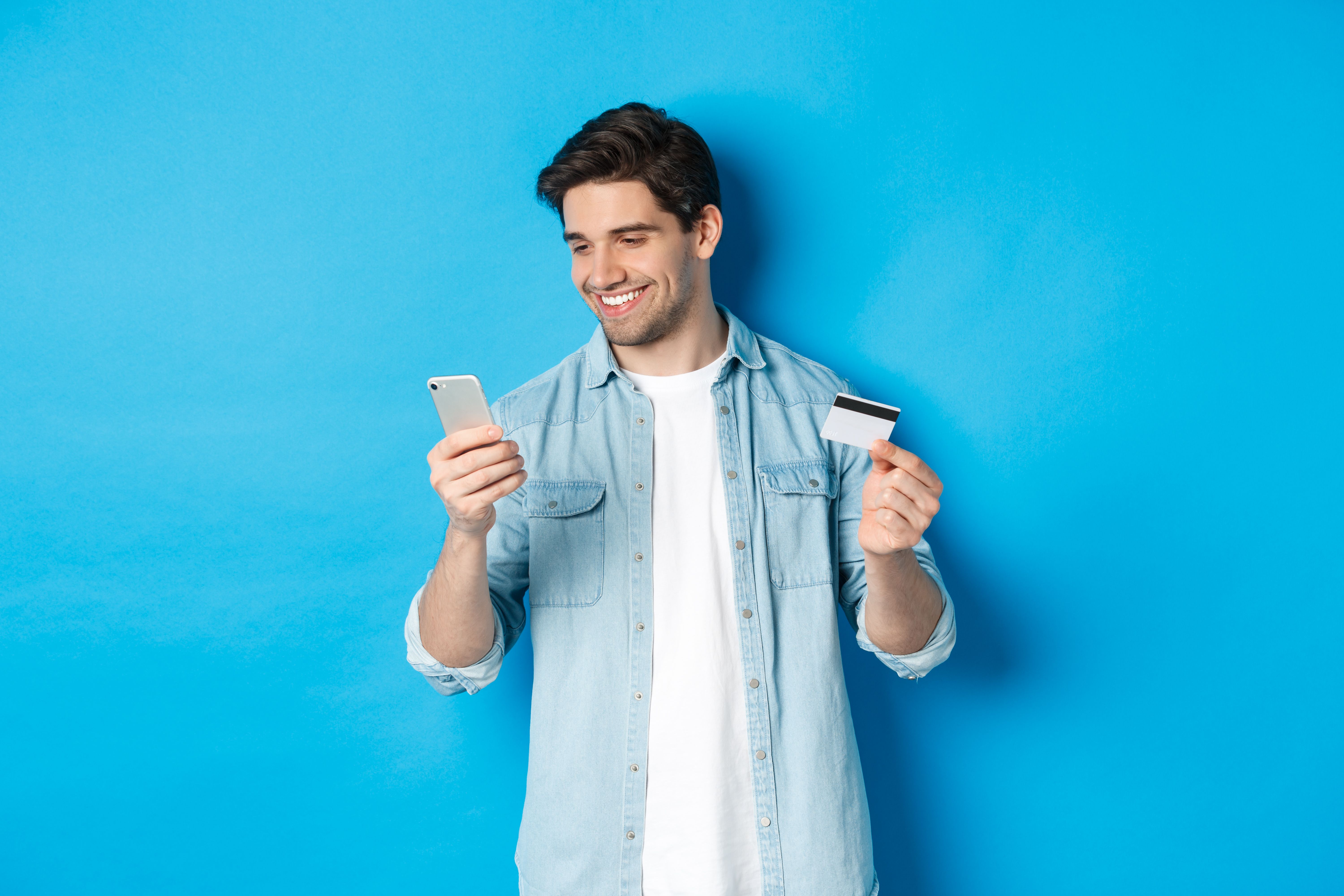 young-man-shopping-online-with-mobile-application-holding-smartphone-credit-card-standing-blue-background.jpg