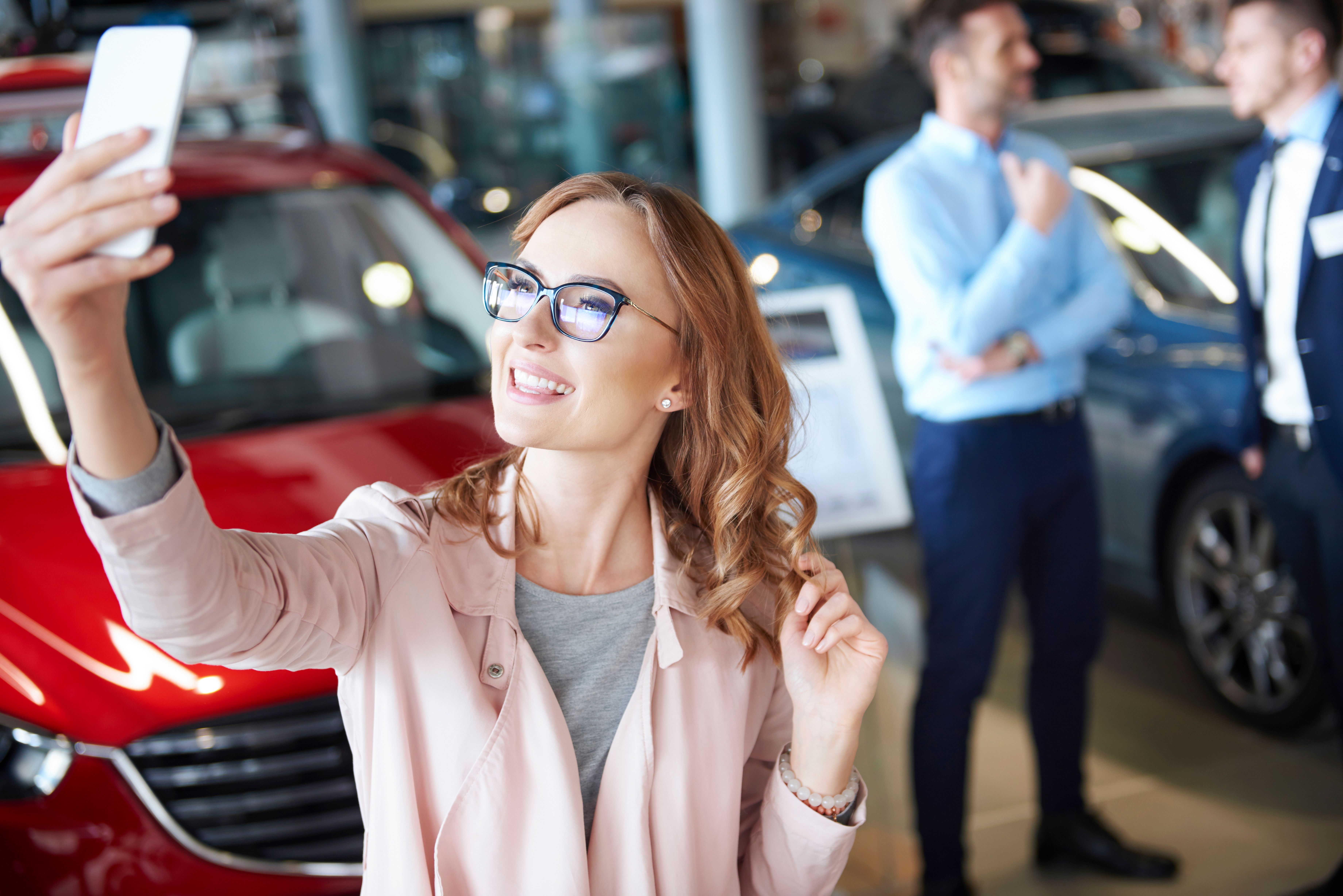 young-woman-taking-picture-car-dealership.jpg